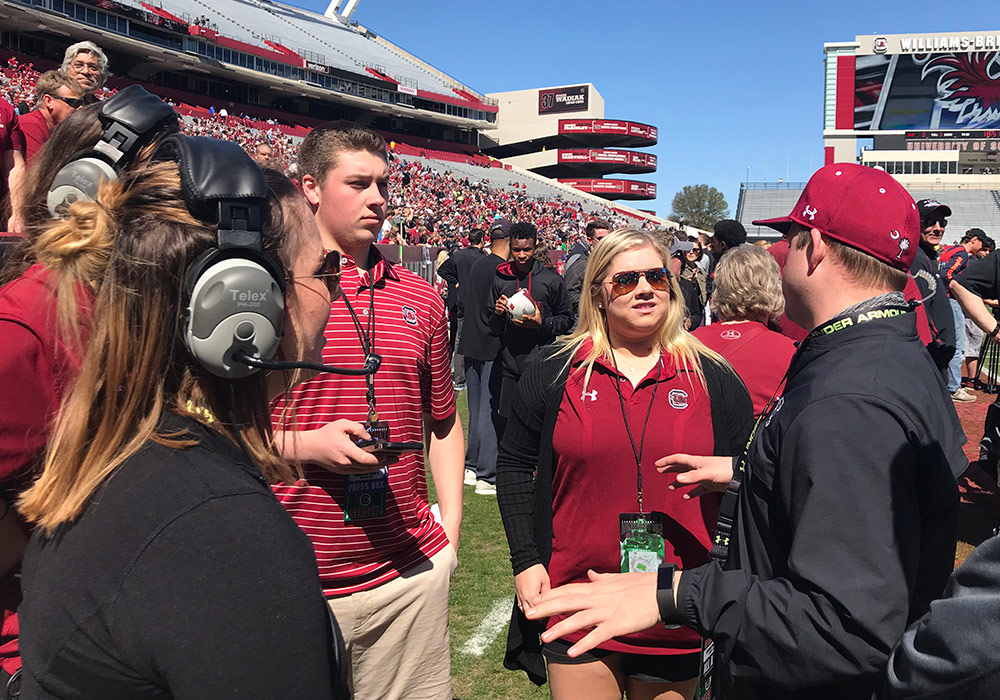 Student interns on the sidelines of a football game.